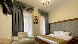 A hotel room with a bed, a sofa, a wooden table, and a chandelier. - Boomerang Business Hotel (Odesa)
