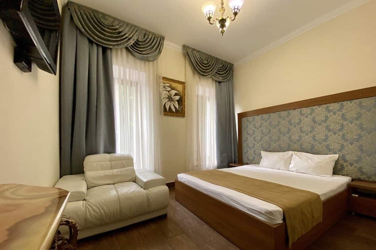 Una habitación de hotel con cama, sofá, mesa de madera y candelabro.