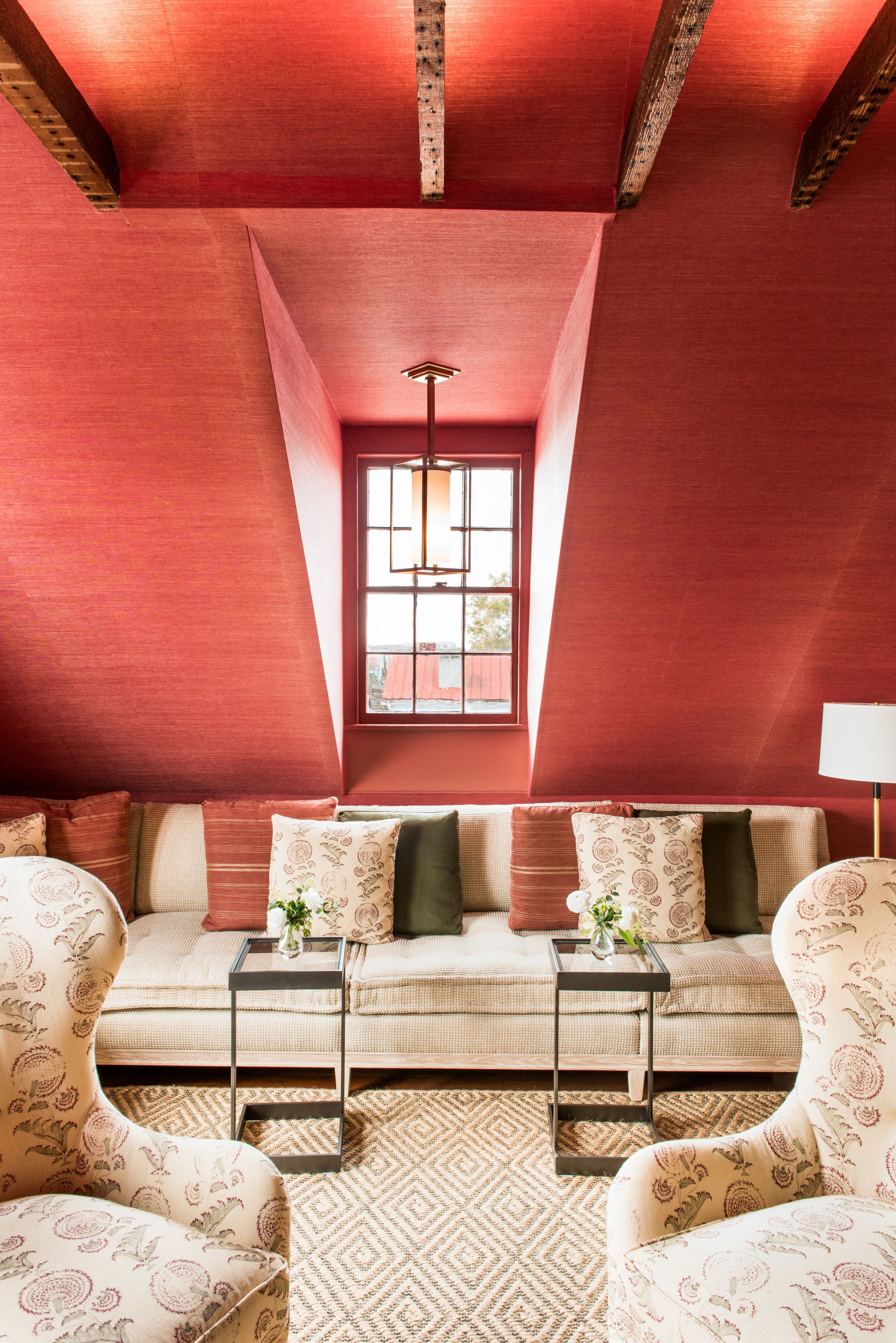A cozy living room with a red ceiling, a sofa set, two side tables, and a window with a view.