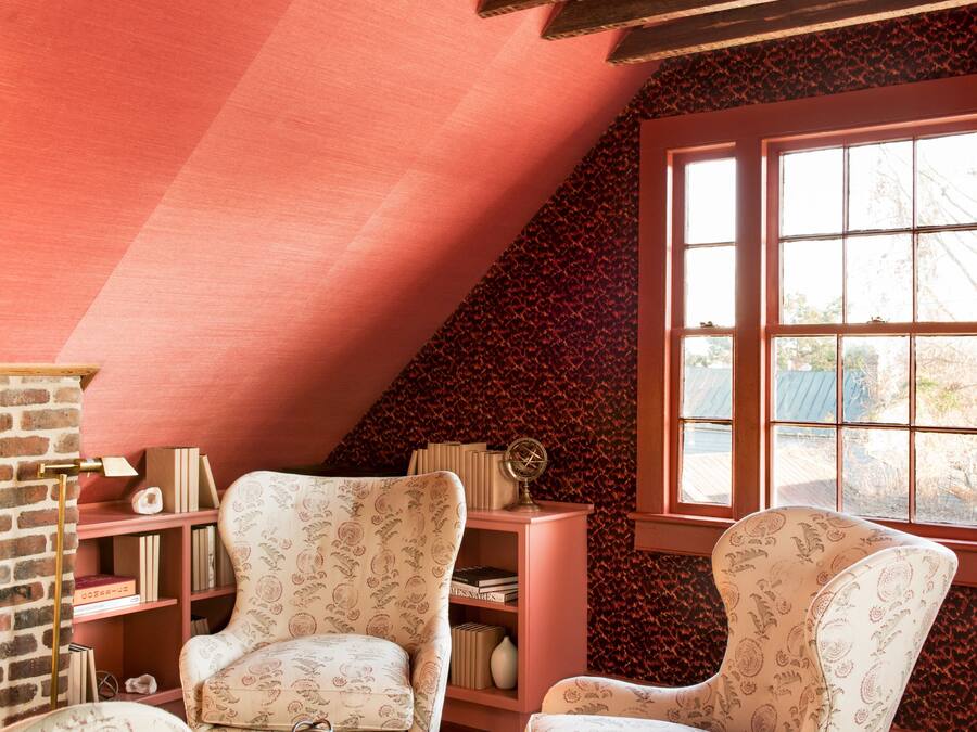 Un acogedor cuarto ático con dos sillones estampados, una mesita y una estantería.
