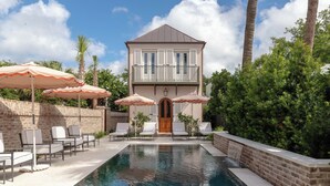 A two-story building with a swimming pool, surrounded by palm trees and outdoor seating with umbrellas. - 86 Cannon Charleston - Adults Only (Charleston)