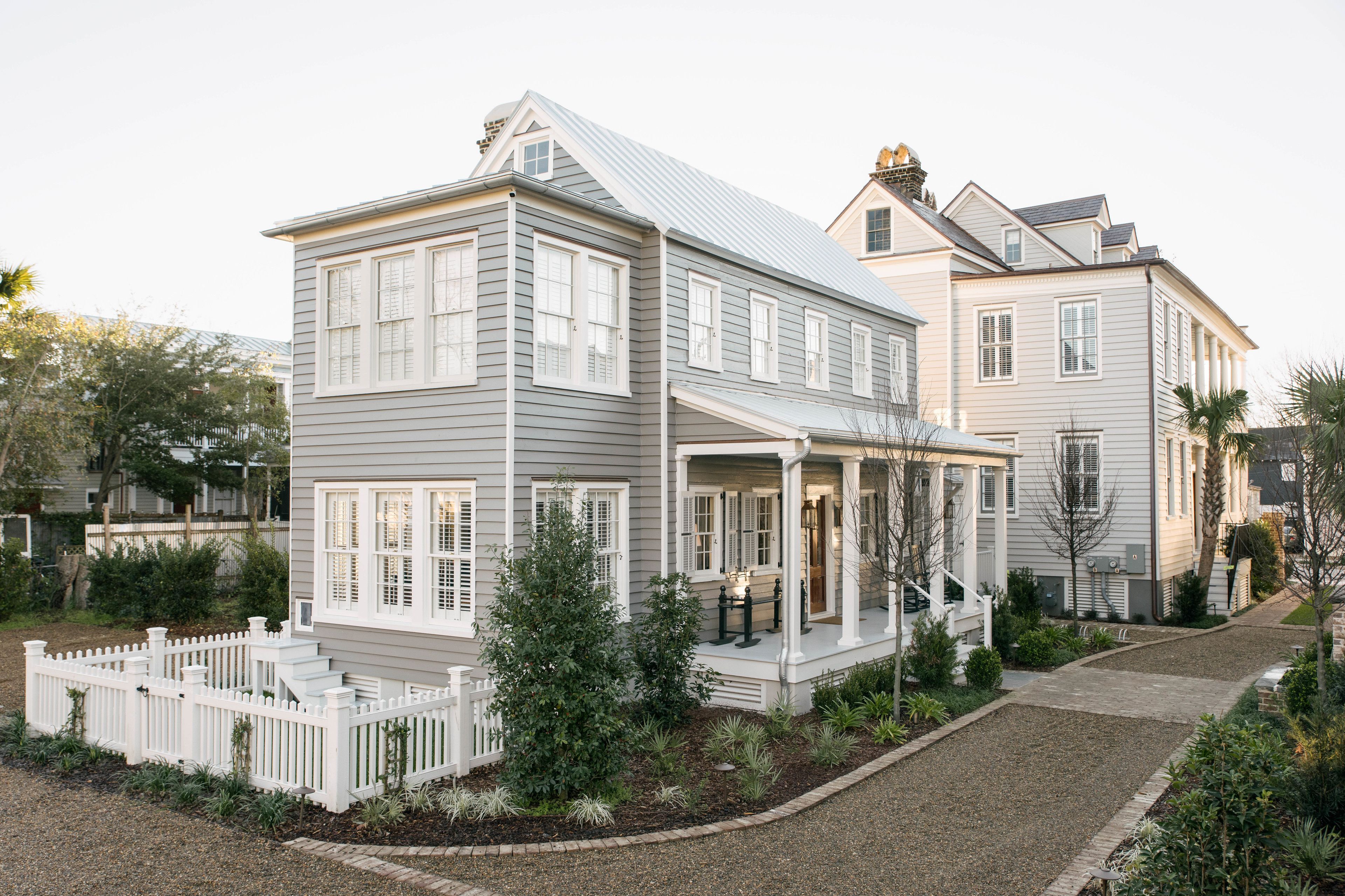 A two-story house with a porch, a white picket fence, and a well-maintained garden.