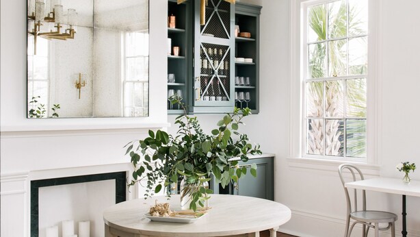 A room with a round table, a chandelier, a fireplace, and a large mirror. - 86 Cannon Charleston - Adults Only (Charleston)