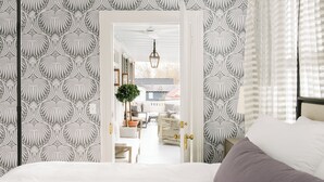 A bedroom with a bed, a door leading to a living area with a sofa and a plant. - 86 Cannon Charleston - Adults Only (Charleston)