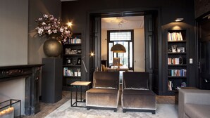 Una sala de estar con chimenea, dos sillones, una estantería y un jarrón grande de flores.