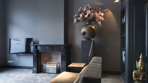Una sala de estar moderna con un sofá, una chimenea, un televisor y una estatua.