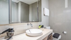 Een moderne badkamer met een grote spiegel, een wastafel, een toilet en een handdoekhouder.