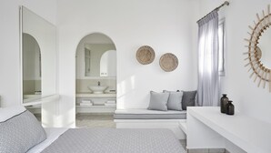 Ein modernes Schlafzimmer mit Bett, Schminktisch mit Spiegel, Bank mit Kissen und einer Wanddekoration.
