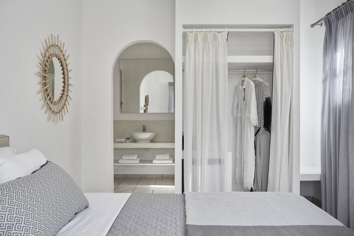 Une chambre d’hôtel moderne équipée d’un lit, d’une coiffeuse avec un lavabo et d’un miroir.