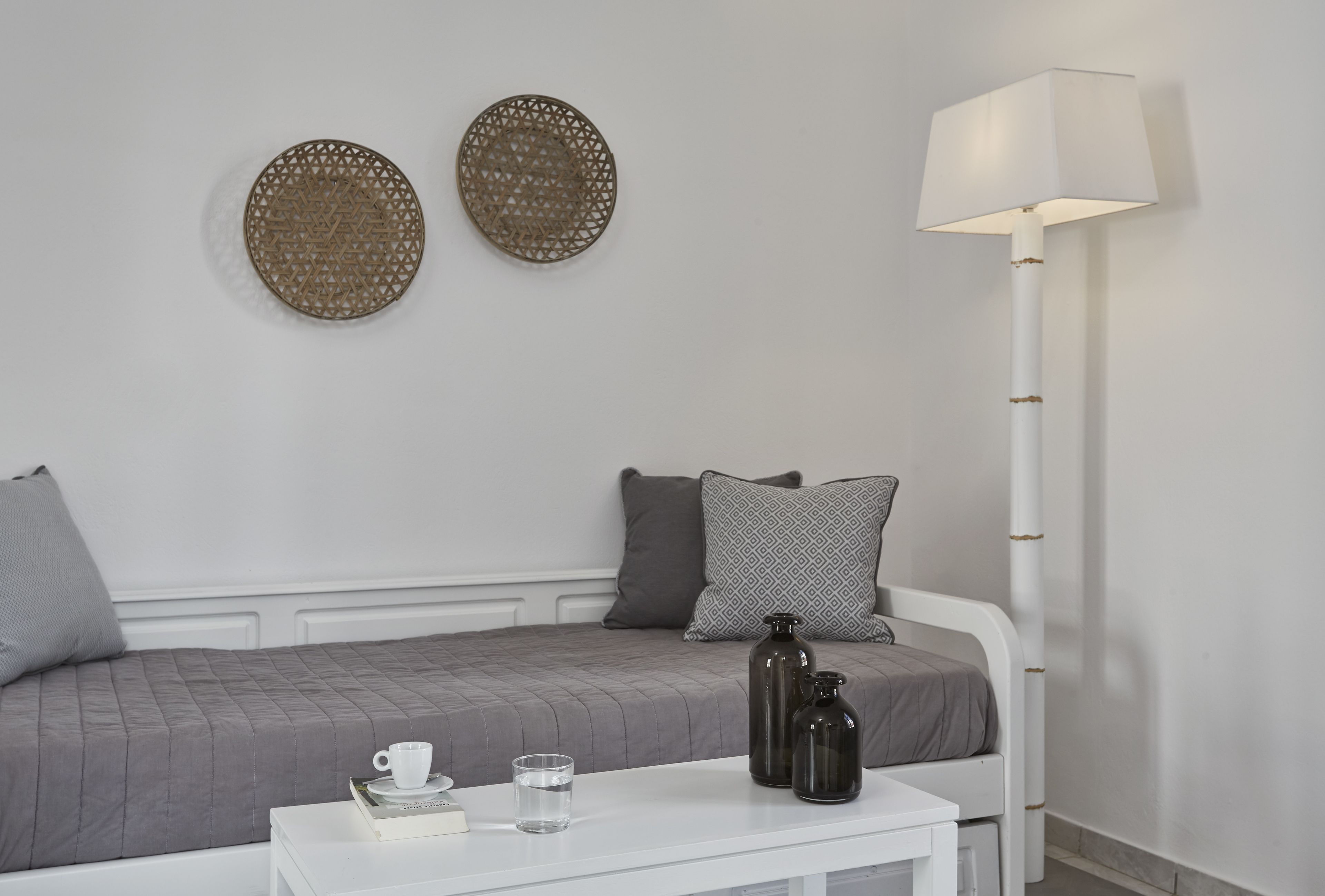 Un dormitorio ordenado con cama, mesita de noche, lámpara y adornos en la pared.
