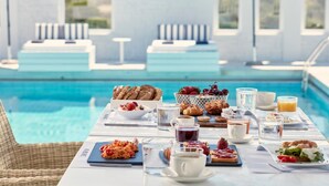 Ein Frühstück am Pool mit verschiedenen Speisen und Getränken.