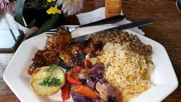 Un plato de comida con arroz, frijoles, carne y verduras sobre una mesa.
