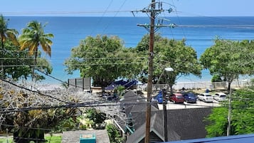 A residential area with a view of the ocean, power lines, and parked cars.