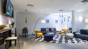 A modern living room with a sofa, chairs, a coffee table, and a TV. - Livris Hotel (Zagreb)