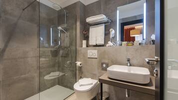 A modern bathroom with a glass-enclosed shower, a toilet, a sink, and a mirror.