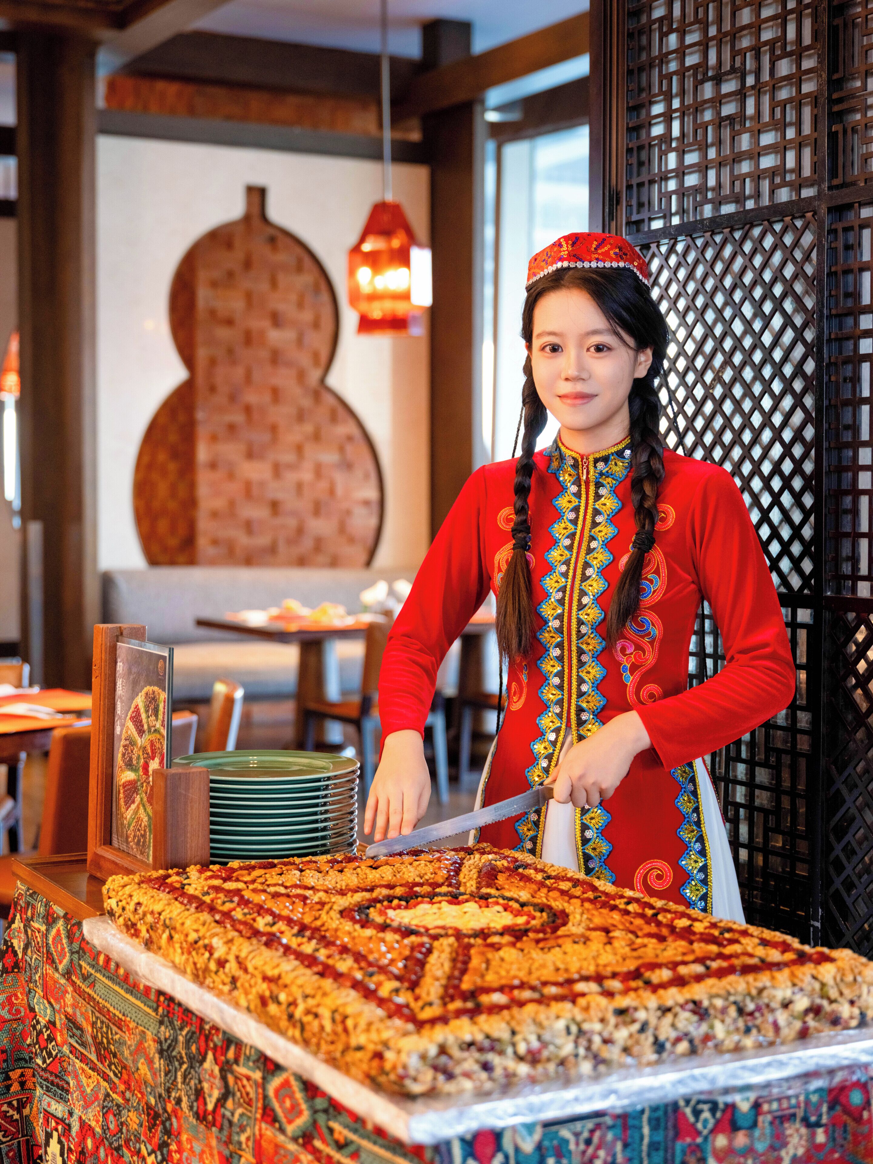 A person serving food at a buffet with a large, intricately decorated dish in the foreground.