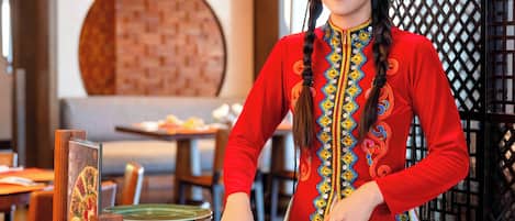 A person serving food at a buffet with a large, intricately decorated dish in the foreground.