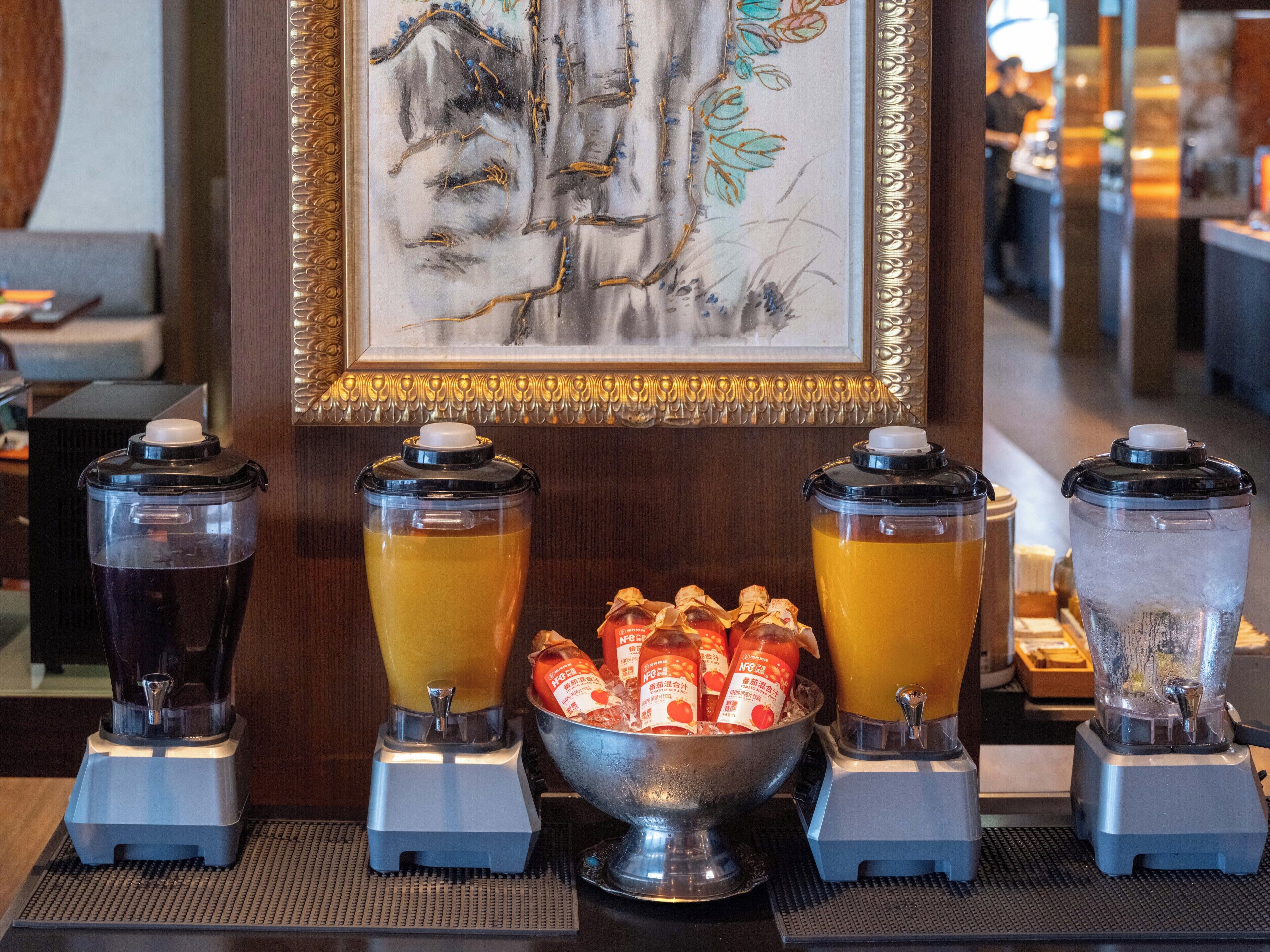 Una zona de bar con tres dispensadores de bebidas, un bol de aperitivos y una obra de arte enmarcada en la pared.