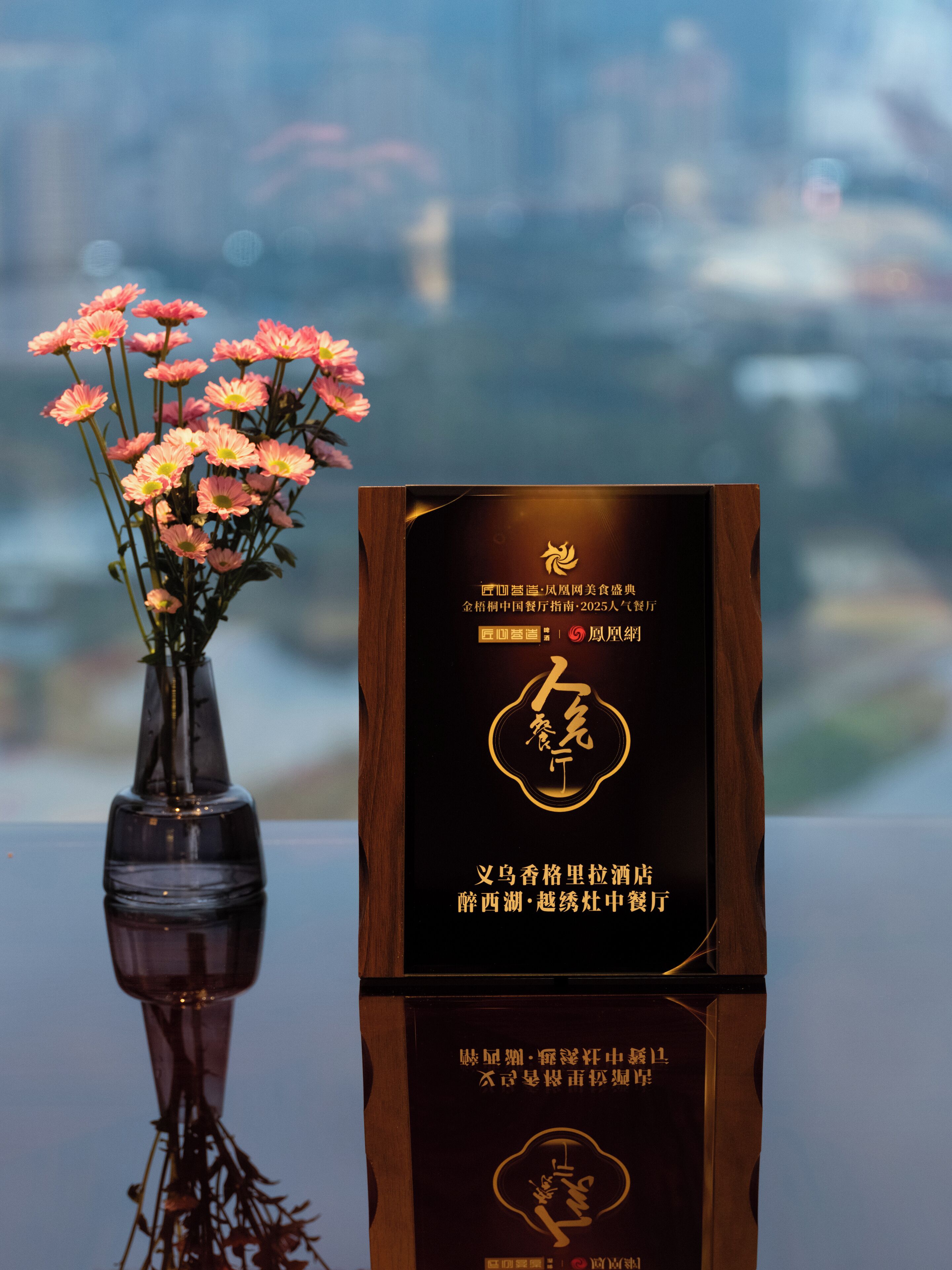 A wooden plaque with Chinese characters and a vase of pink flowers.