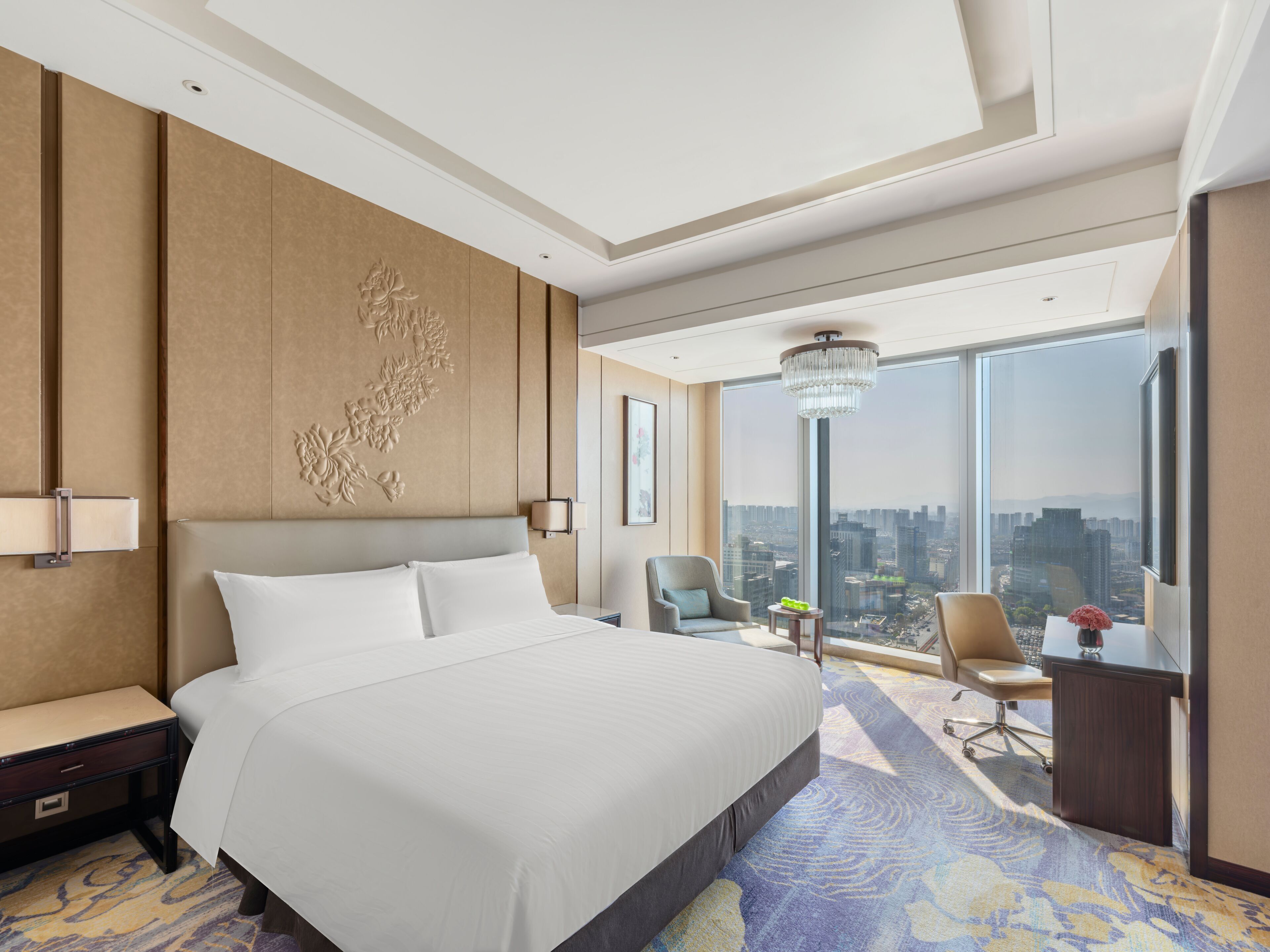 Una habitación de hotel moderna con una cama grande, un escritorio, una silla y vistas de la ciudad.