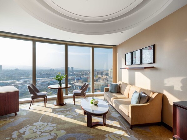 A modern living room with a large city view, a sofa, two armchairs, a coffee table, and a small table with a vase. - Shangri-La Yiwu (Jinhua)