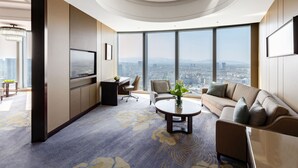 Een moderne hotelkamer met een groot raam met uitzicht op de stad, een ronde salontafel en een comfortabele zithoek.