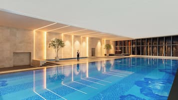 Una piscina interior con suelo de baldosas, una persona de pie junto a la piscina y una zona de bar con un ventanal grande.