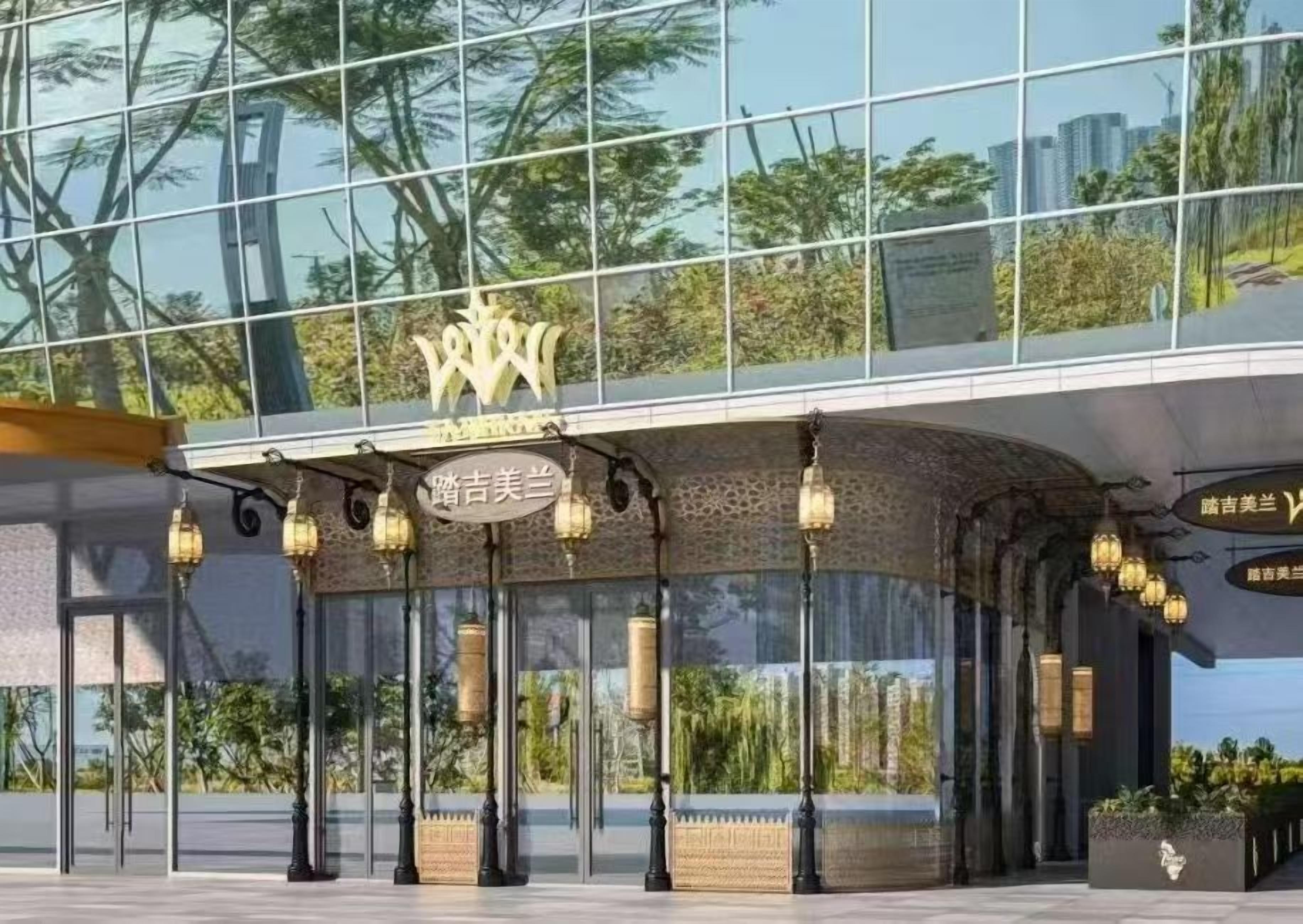 A modern building with a glass facade, a traditional archway entrance, and decorative lanterns.