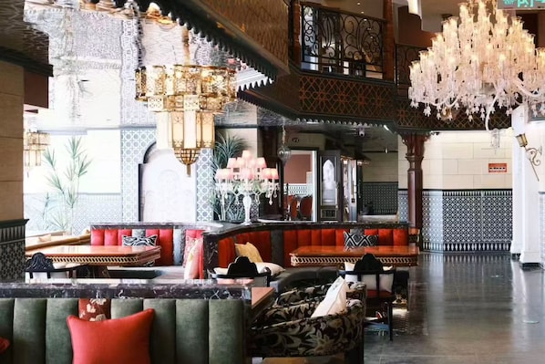 A lobby with a grand chandelier, seating areas, and a patterned wall.