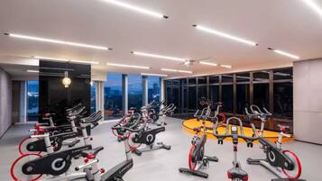 A modern gym with stationary bikes, large windows, and a city view.