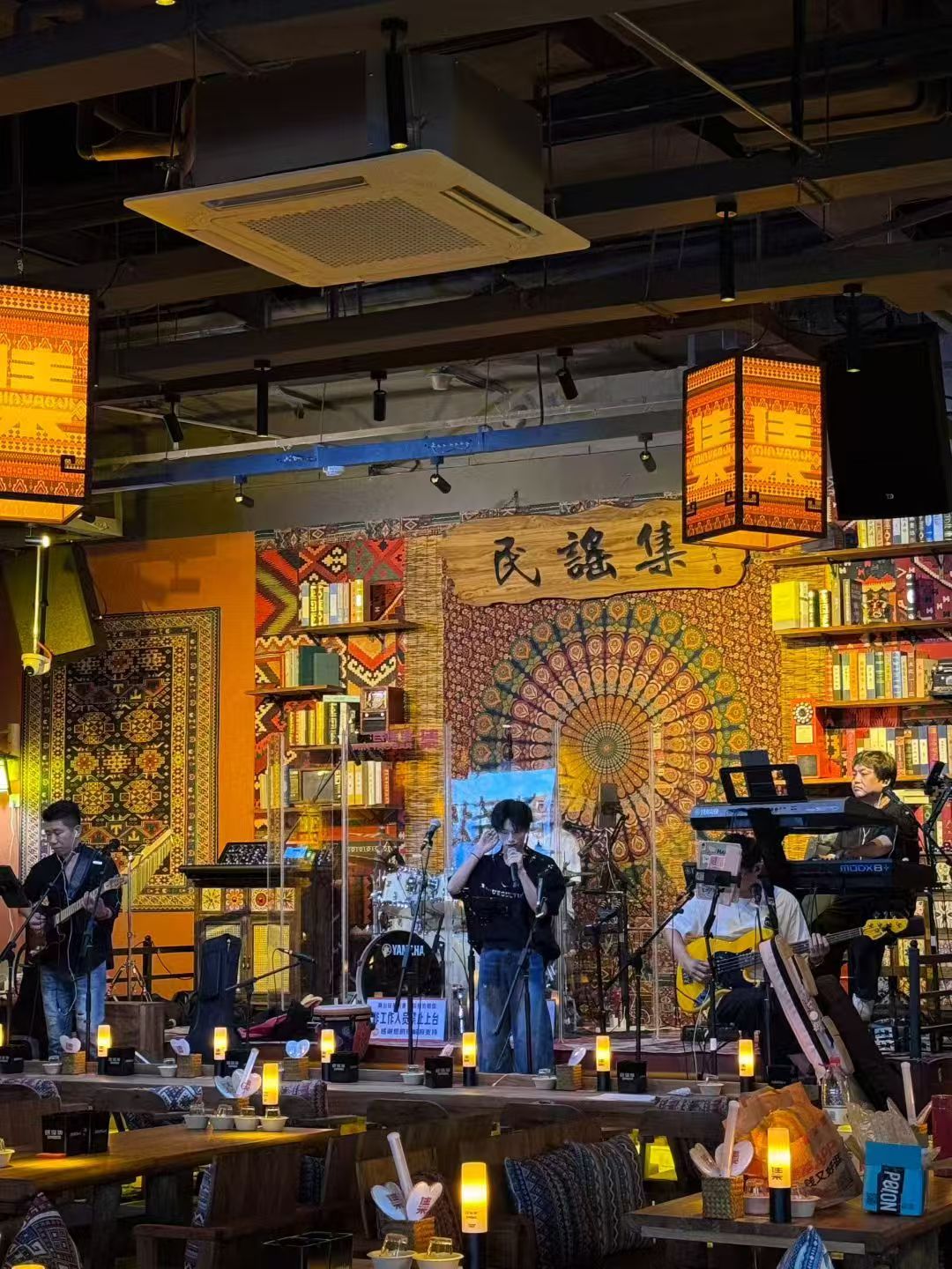 A music venue with a stage, performers, and a vibrant, patterned wall.