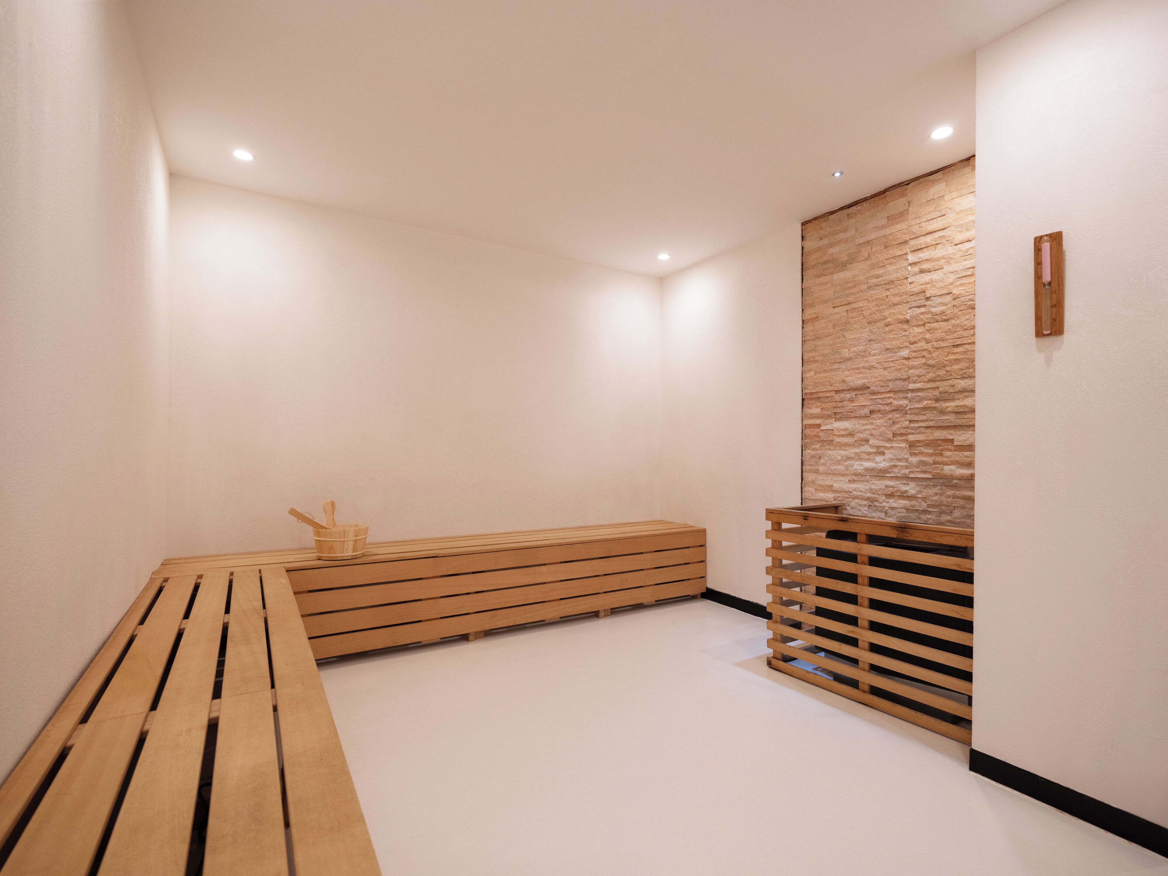 A modern, minimalist room with a wooden bench, a small table with a cup and spoon, and a textured wall.