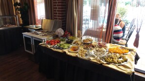 A buffet table with various food items, a coffee station, and a view of the outdoors through large windows. - Cantilena Complex (Sunny Beach)