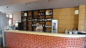A bar area with a brick counter, shelves of liquor bottles, and a refrigerator. - Cantilena Complex (Sunny Beach)