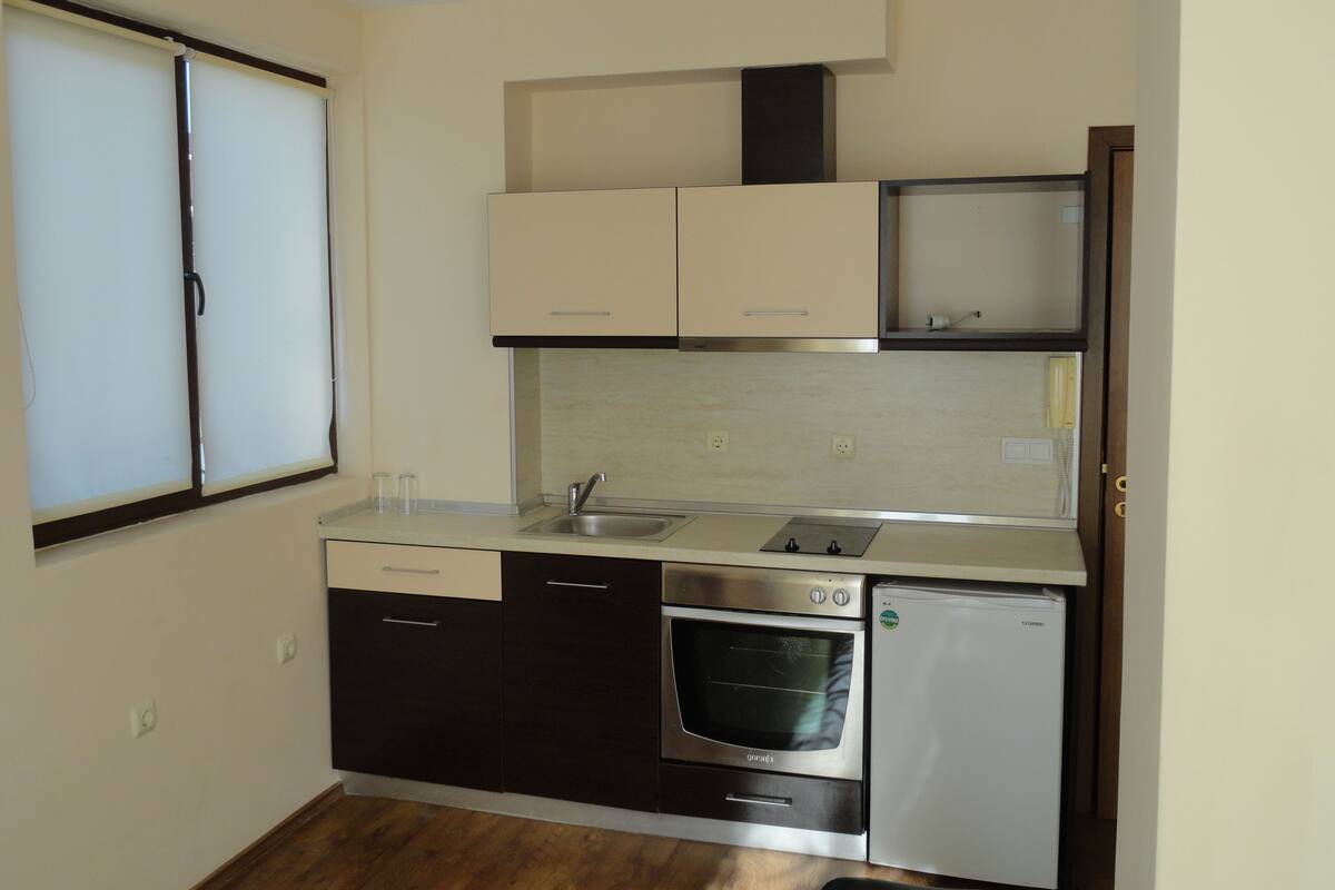 Una cocina compacta con horno integrado, refrigerador y pileta.