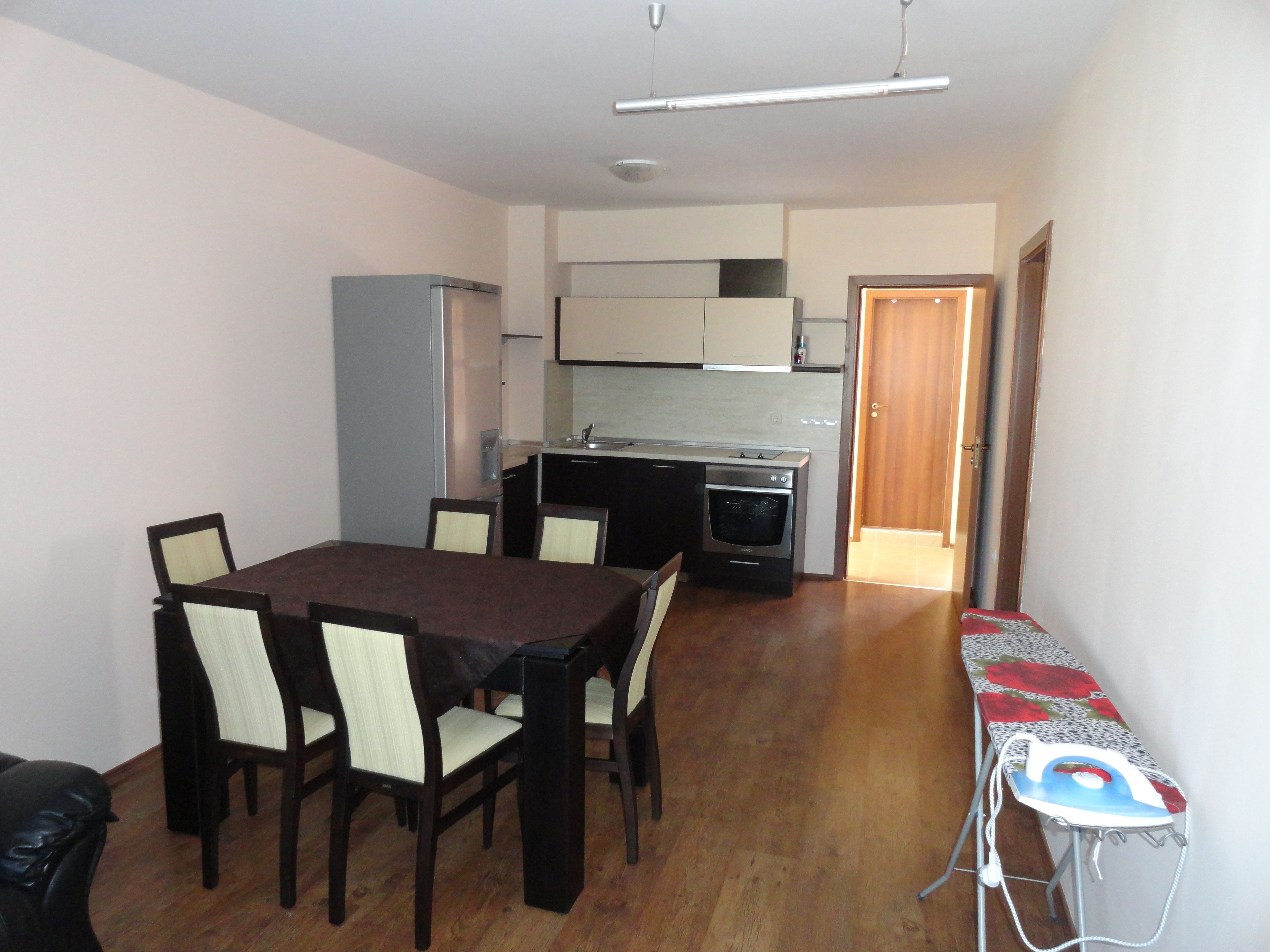 Un espace de vie compact comprenant un coin repas, une kitchenette et un petit coin dédié au repassage.