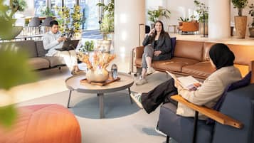 A modern lounge area with leather sofas, a coffee table with a vase, and potted plants.