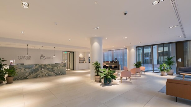 En modern hotellobby med en receptionsdisk, en sittgrupp och stora fönster.