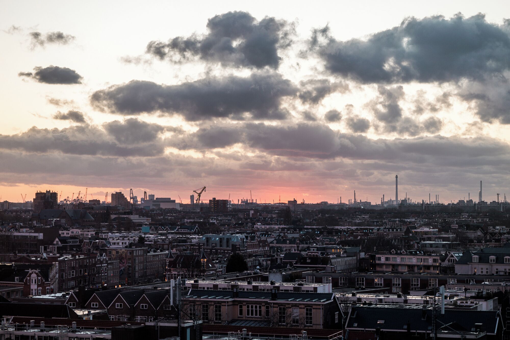 Un paisaje urbano con edificios densos, una torre destacada y un cielo al atardecer.