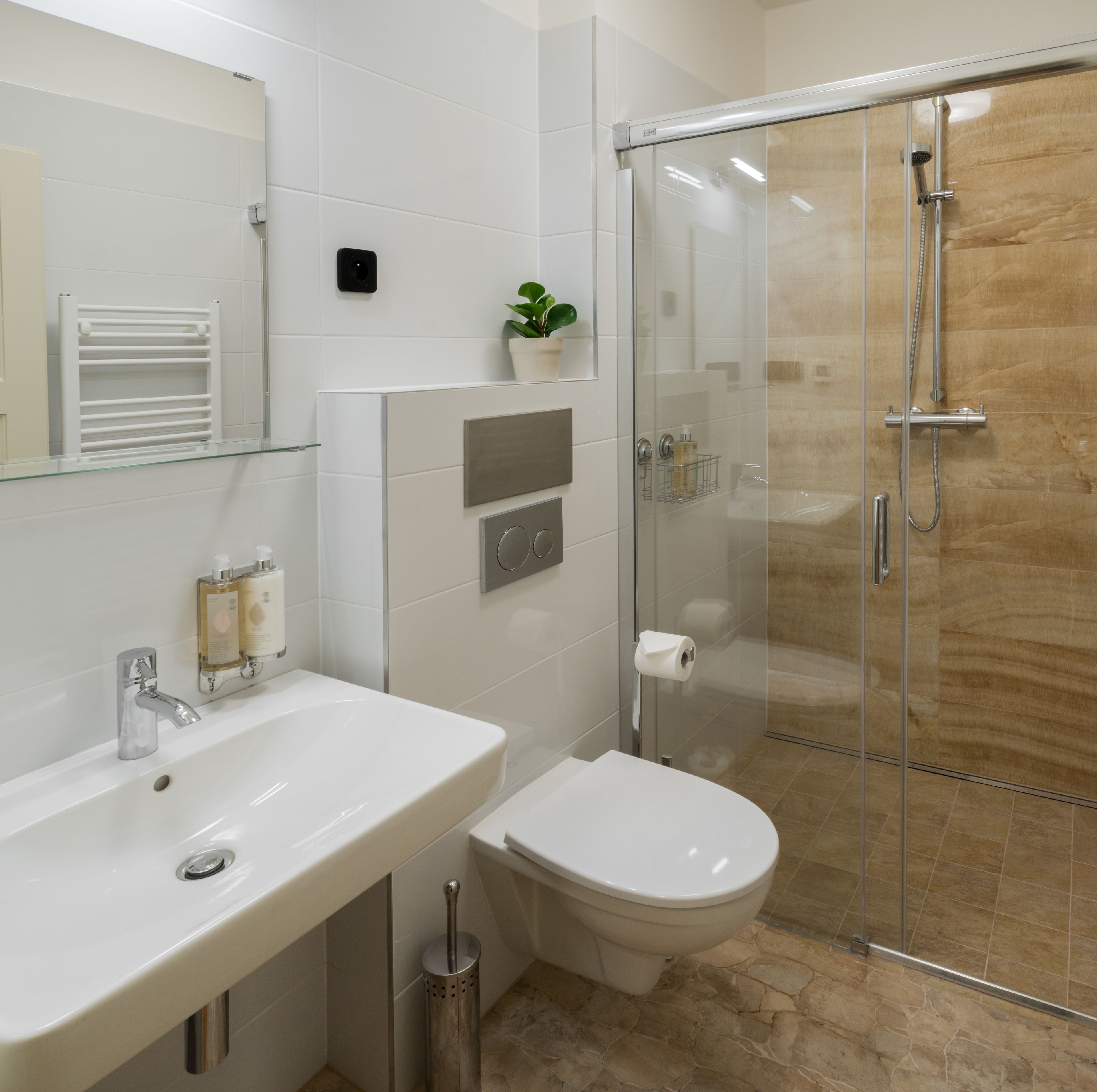 Un baño moderno con cabina de ducha de vidrio, un lavabo blanco con espejo y un inodoro.