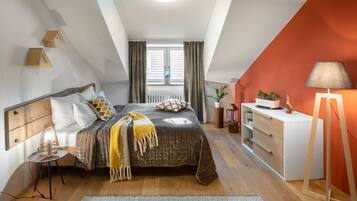 Een slaapkamer met een bed, nachtkastje, lamp, kaptafel en raam.