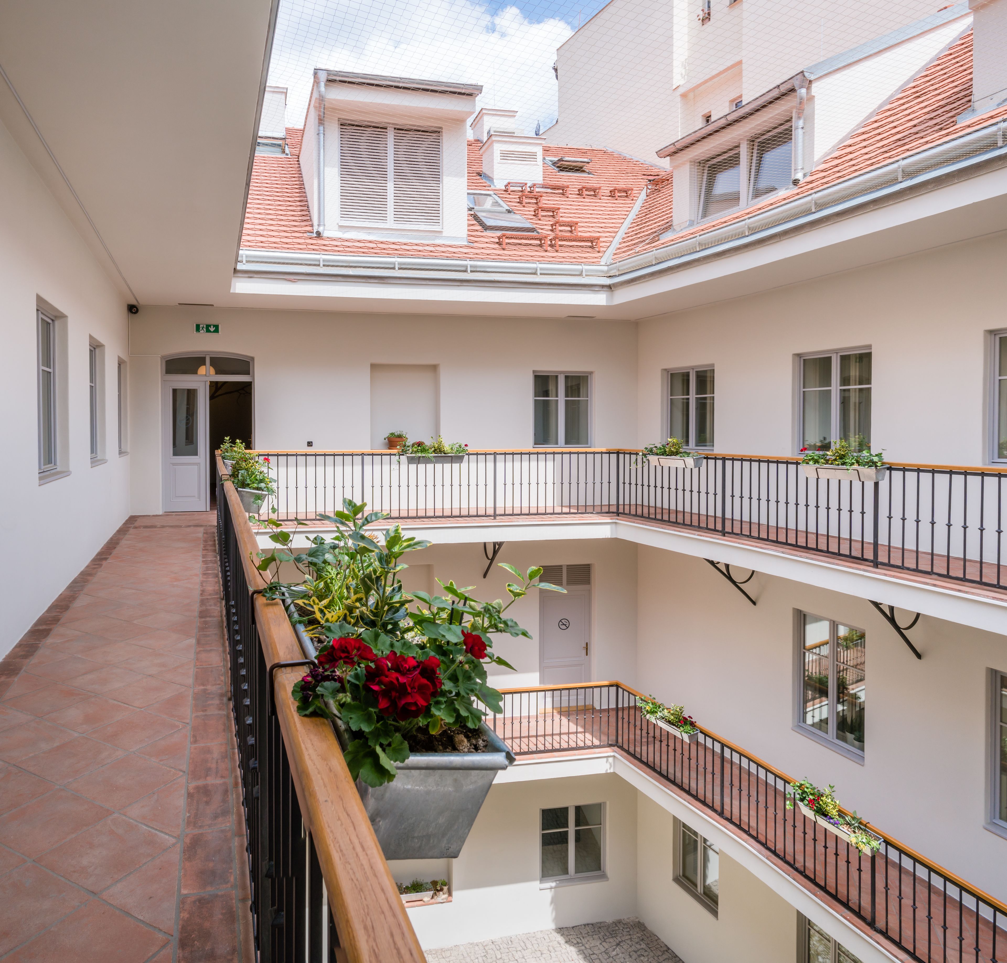A multi-level building with a central courtyard, balconies with railings, and potted plants.