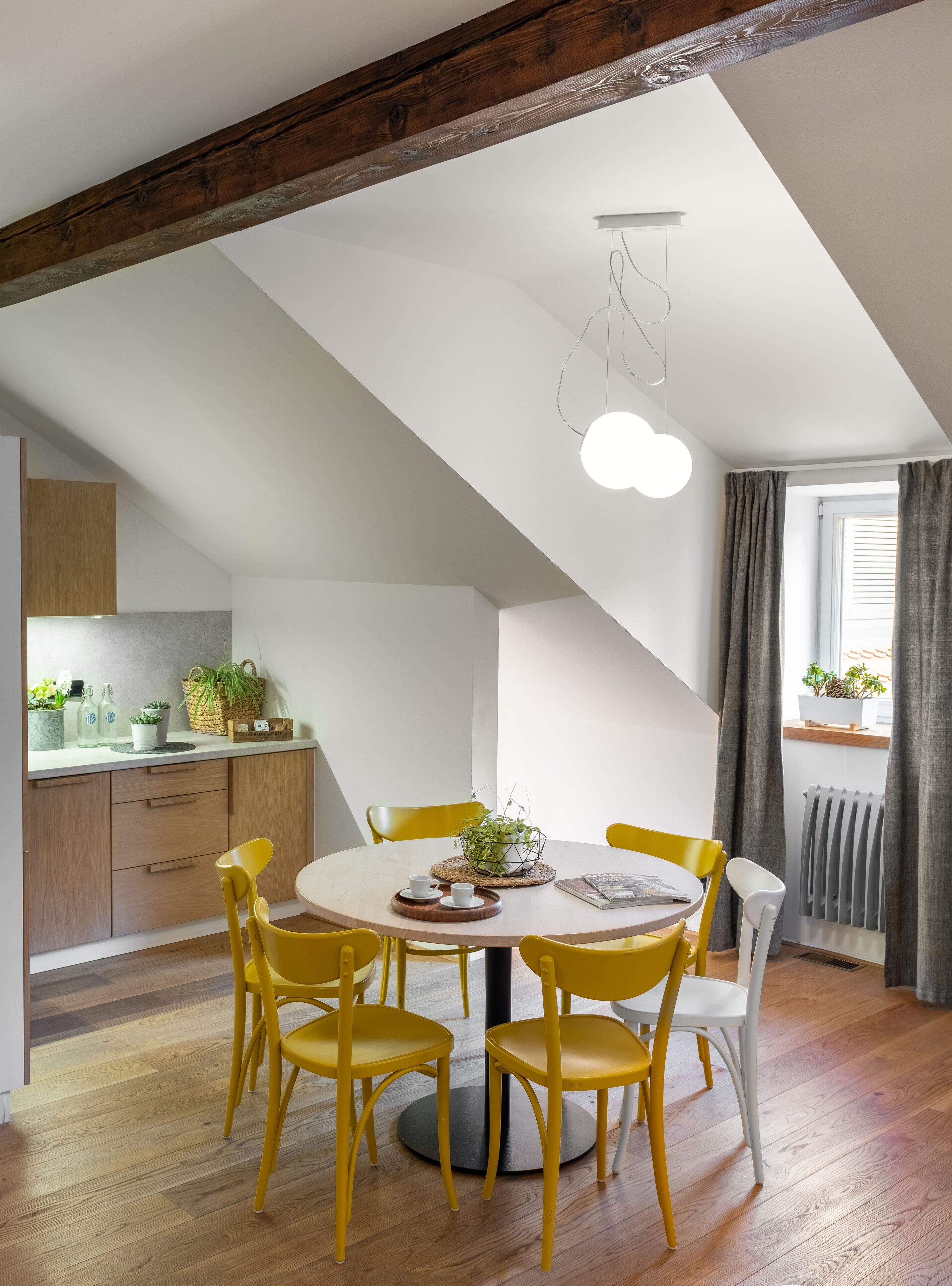 A dining area with a round table, yellow chairs, and a modern pendant light.