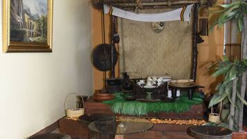 Una habitación tradicional con techo de paja, un cuadro en la pared y una mesa de madera con taburetes.