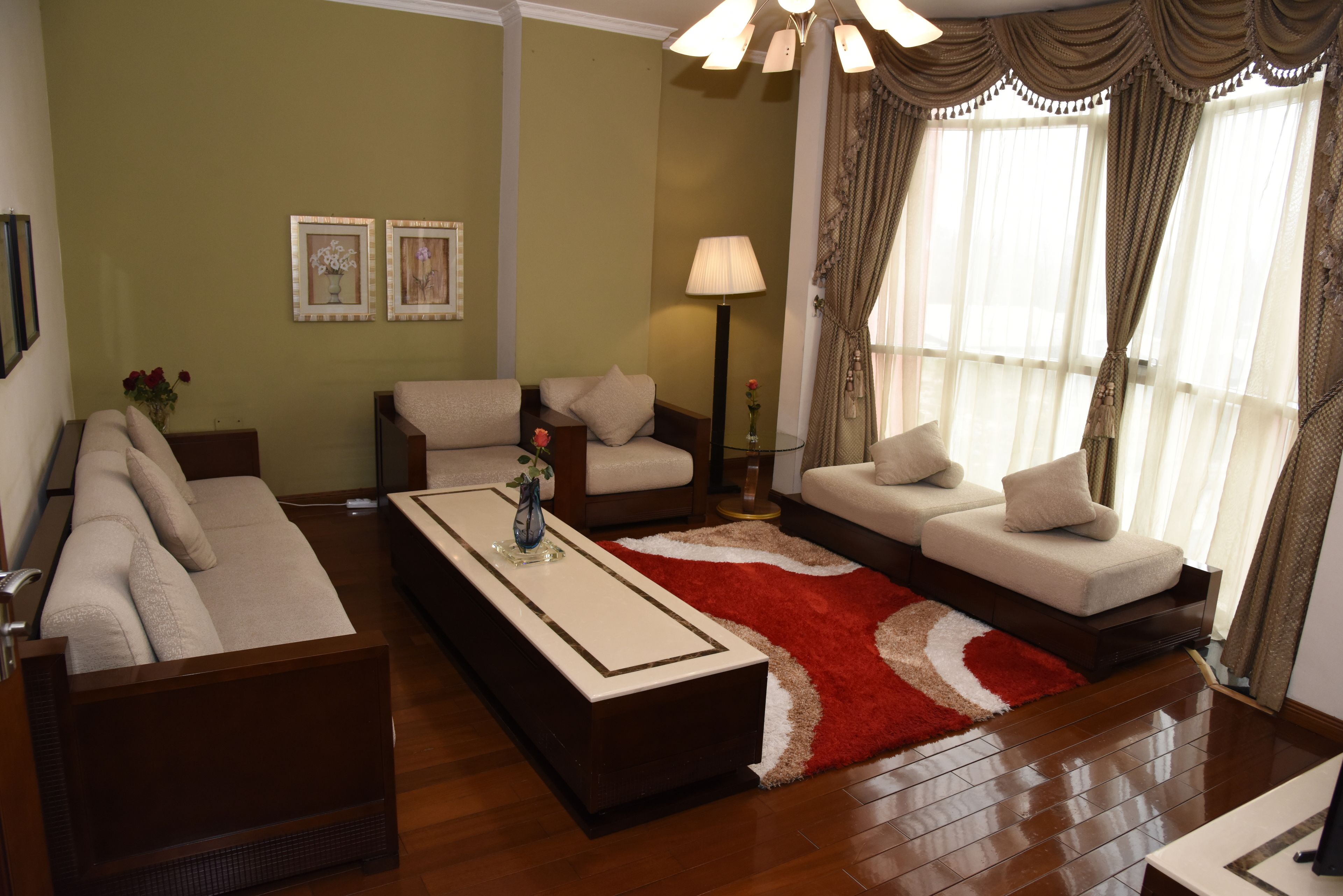 A living room with a sofa set, a coffee table, and a red rug.