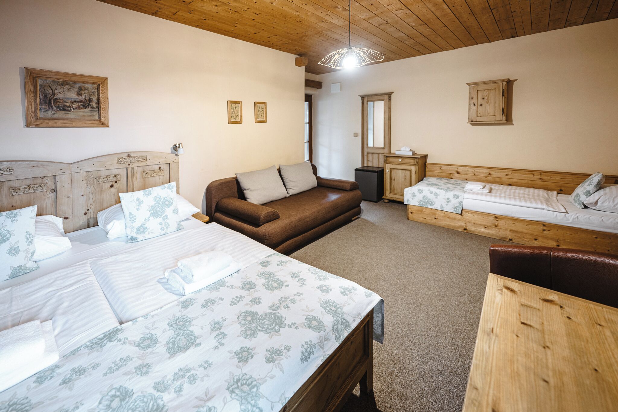 Um quarto aconchegante com duas camas, um sofá e uma mesa de madeira.