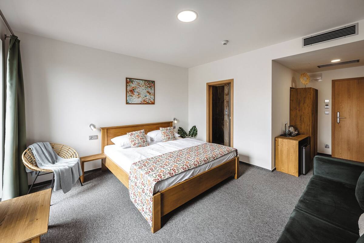 A neatly arranged bedroom with a wooden bed, a small bedside table, a chair, and a wardrobe.