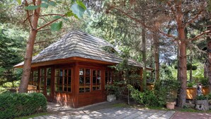 A wooden cabin with a tiled entrance, surrounded by trees and greenery. - Hotel Frýdl (Prague)