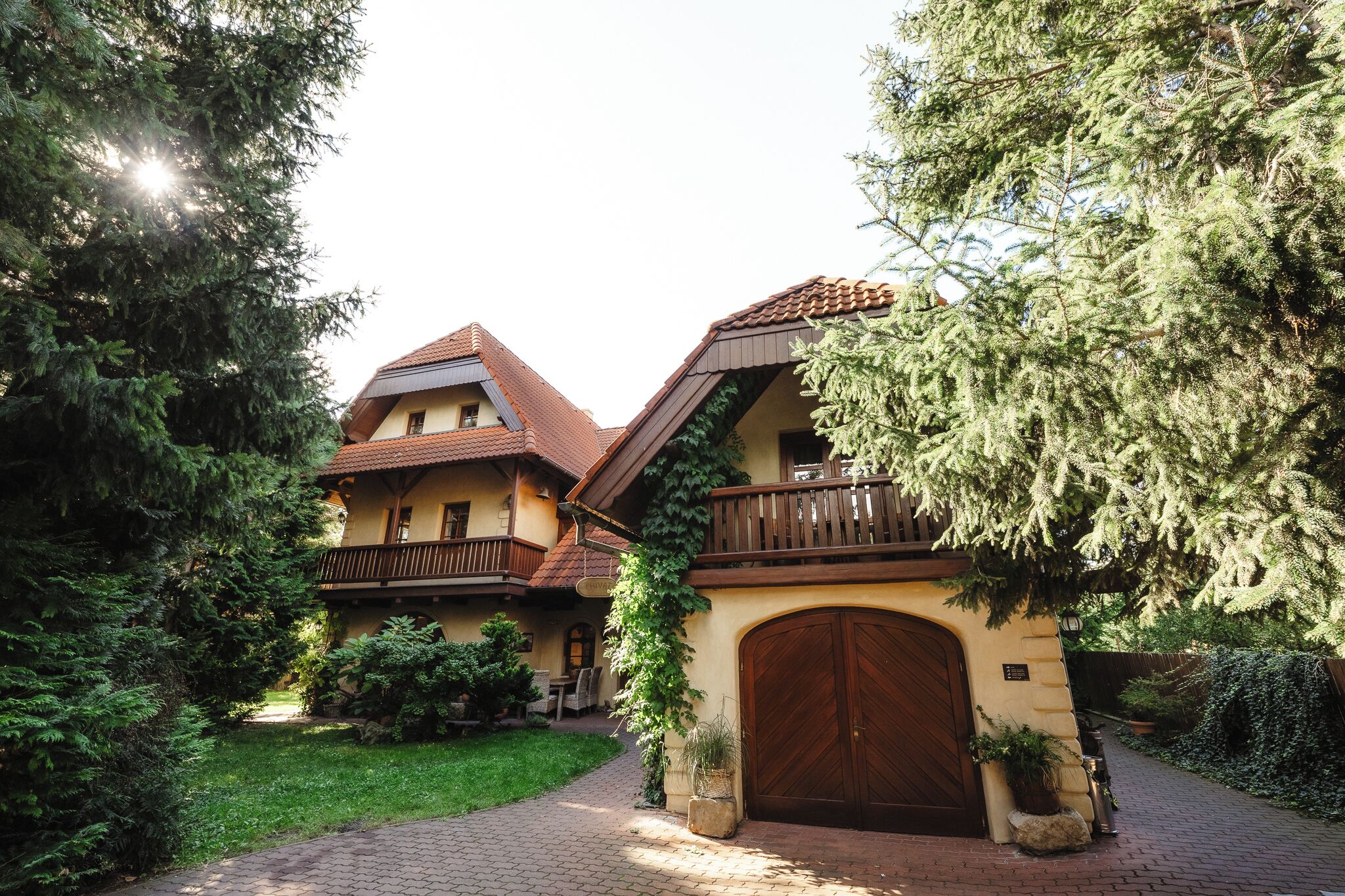 Un bâtiment traditionnel doté d’un balcon en bois, d’une grande porte en bois et d’un jardin bien entretenu.