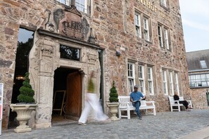 A stone building with a large arched entrance, a sign reading "KASSEL," and a cobblestone street.